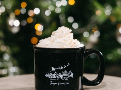 holiday Coquito cocktail with whipped cream in front of a christmas tree