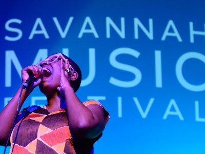A young woman singing into a microphone on stage.