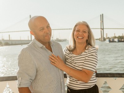 A couple posing for a photo on the outdoor deck of a riverboat.