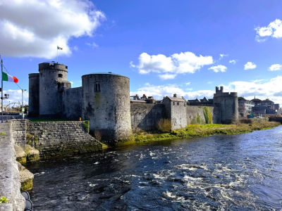 An exterior view of a historic castle surrounded by water in Limerick Ireland.
